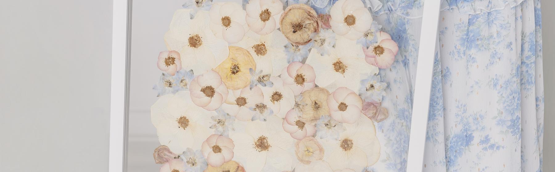Close-up of a finished pressed-flower arrangement under glass