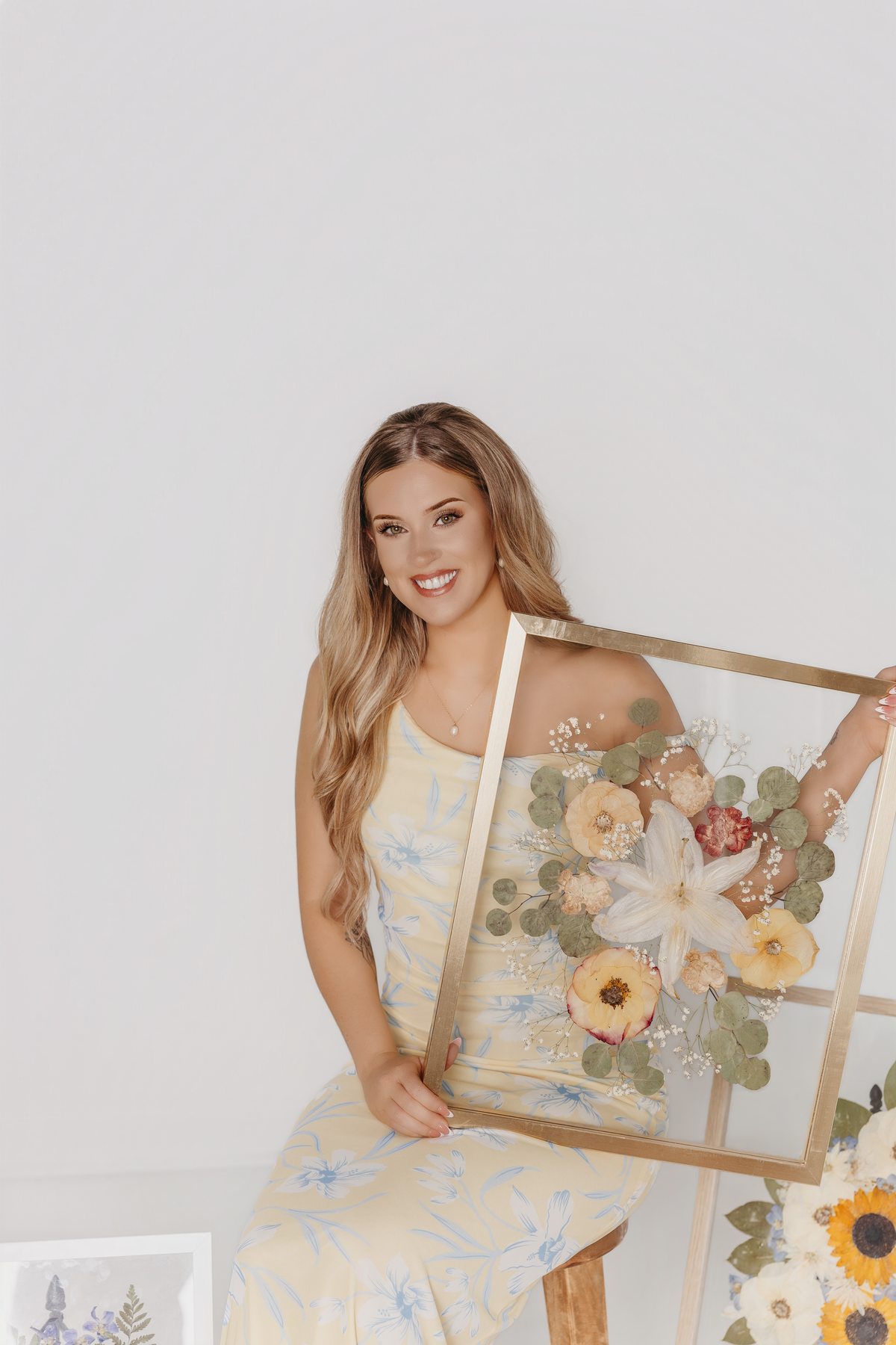 The maker holding a framed pressed-flower keepsake